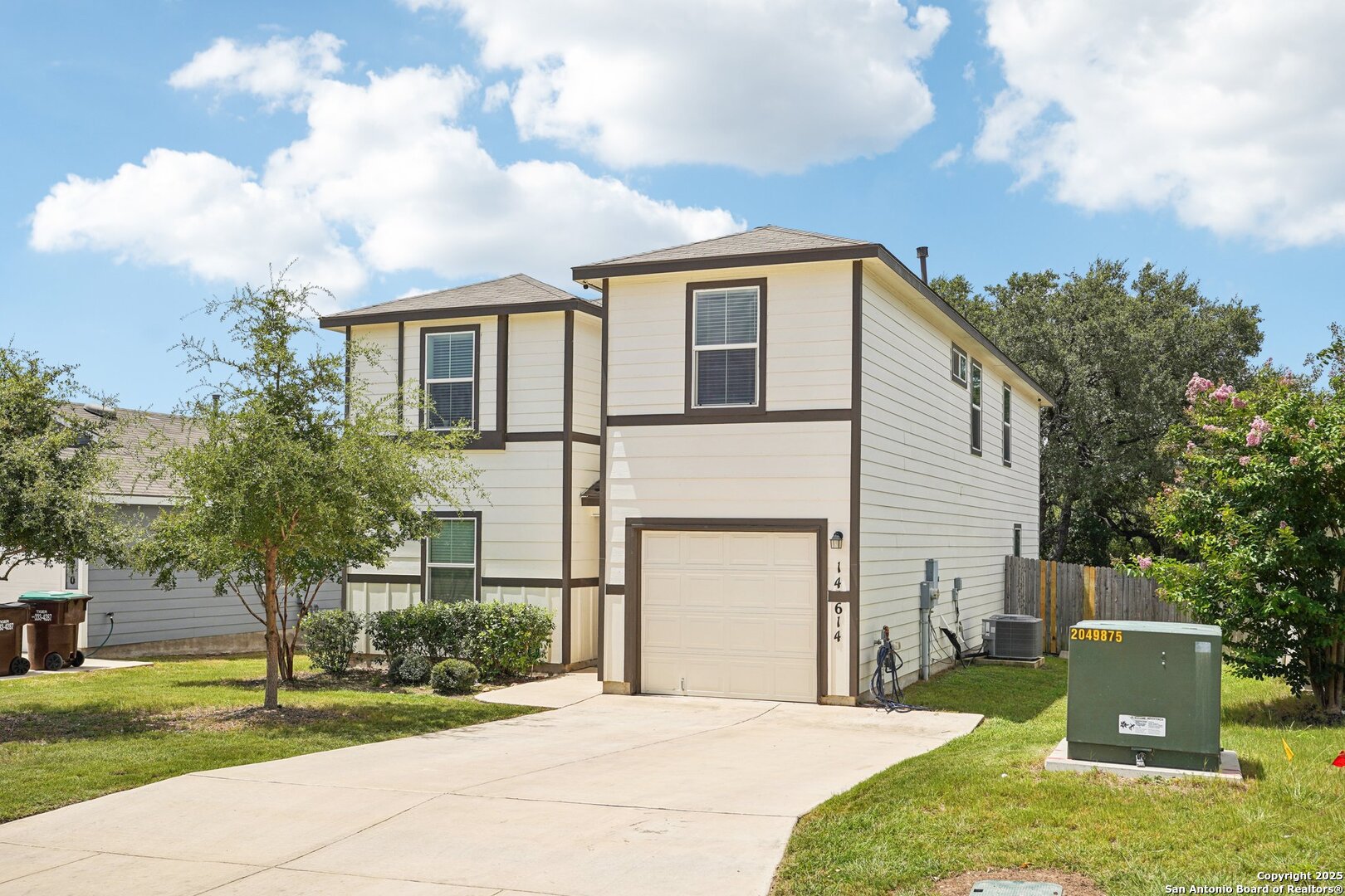 Two-story cream house with dark trim, a single-car garage, and a wide concrete driveway.