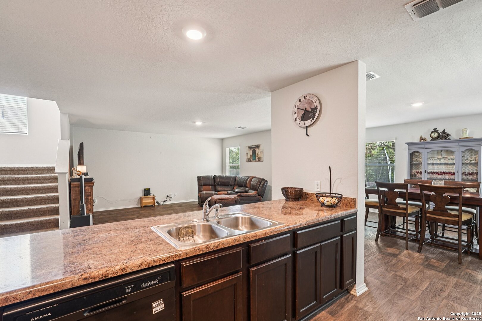 Open-plan kitchen with granite island and double sink, overlooking the living and dining areas.
