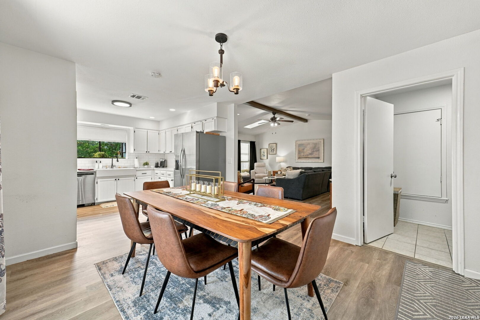 Dining area with a wooden table and upholstered chairs beside an open kitchen and living room.