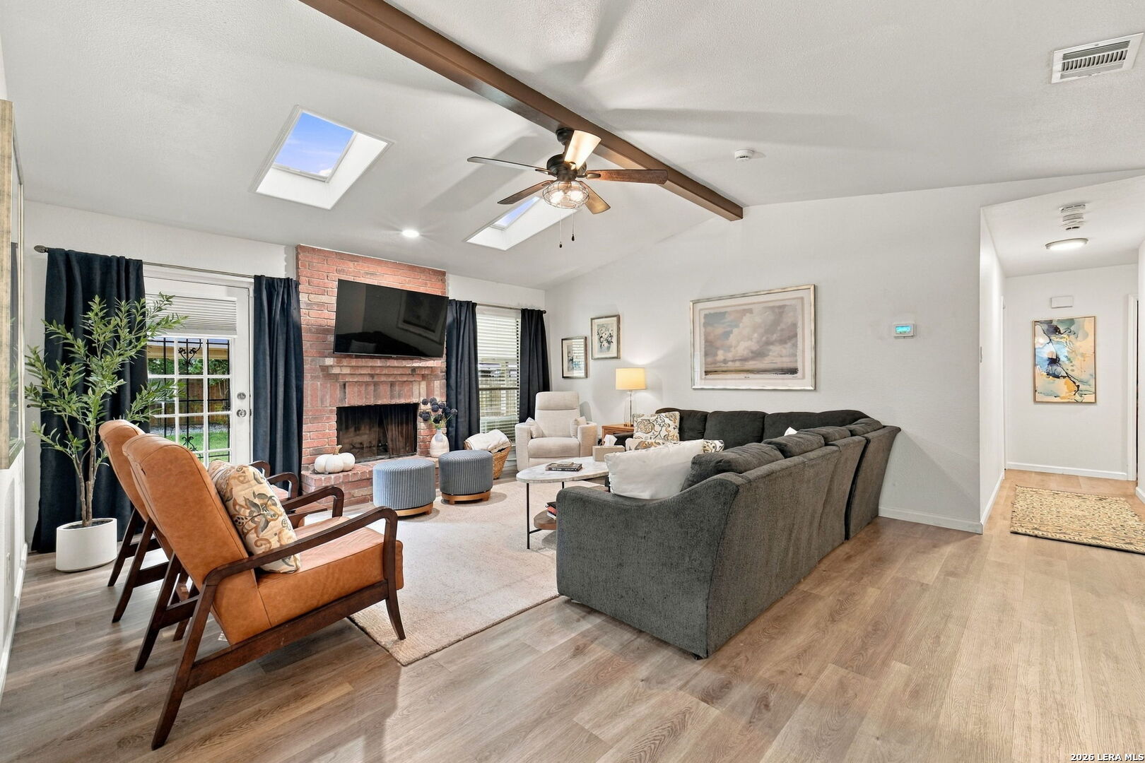 Living room with brick fireplace, skylights, and a large gray sectional sofa.