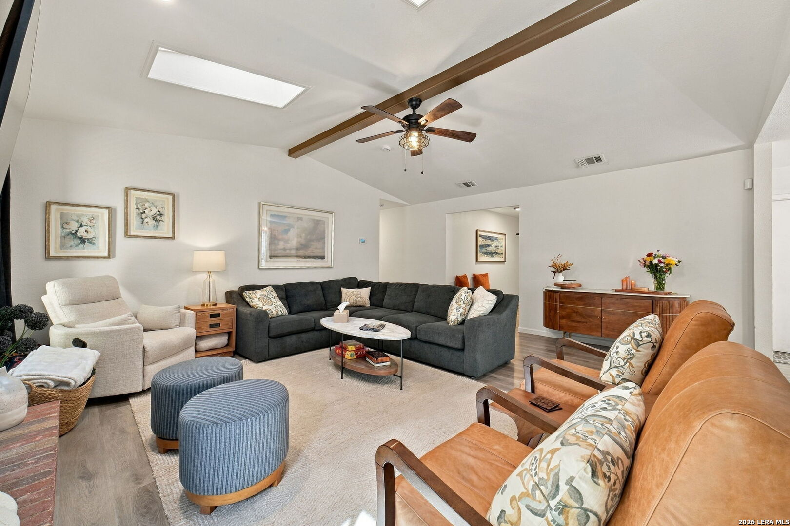 Living room with a charcoal sectional, tan leather armchairs, and a vaulted ceiling with a ceiling fan.