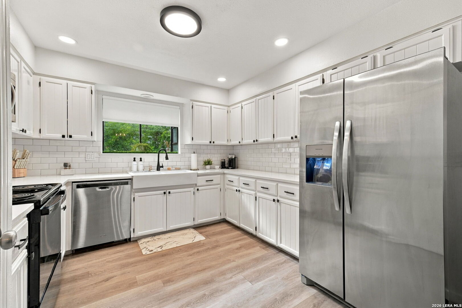 Kitchen with white shaker cabinets, a farmhouse sink, and stainless steel appliances.