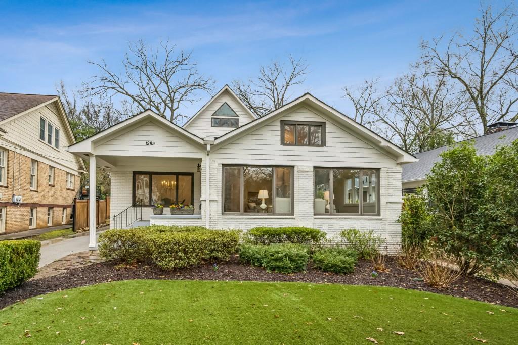 White brick house with covered porch, broad front windows, and landscaped front lawn.