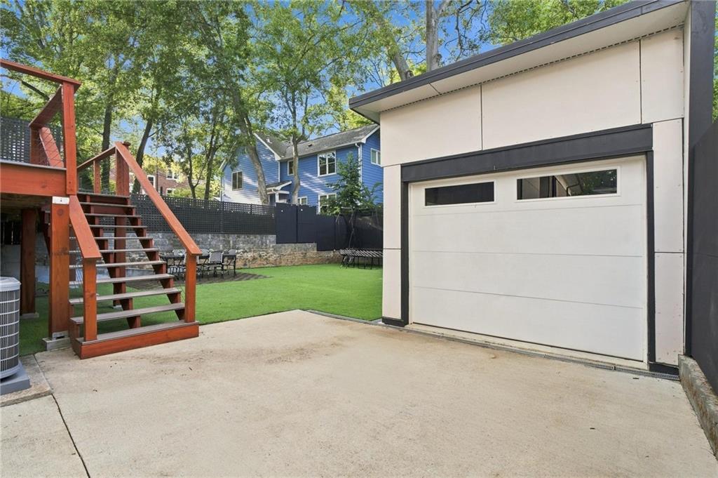 Backyard with a white garage, raised wooden deck, and fenced lawn.