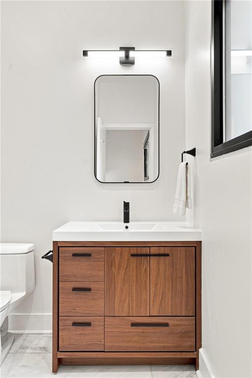 Modern bathroom with a walnut vanity, black faucet, rounded mirror, and partially visible toilet.