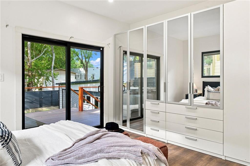 Bedroom with mirrored wardrobes and sliding glass doors opening onto a wooden deck.