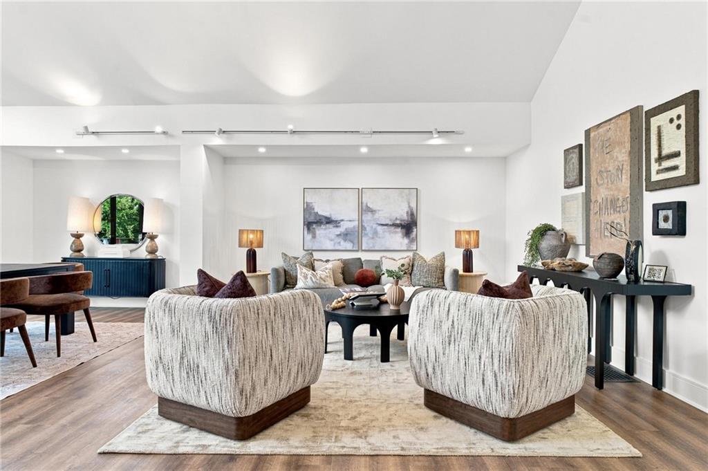 Living room with textured chairs, a sofa, abstract art, and a dining area.