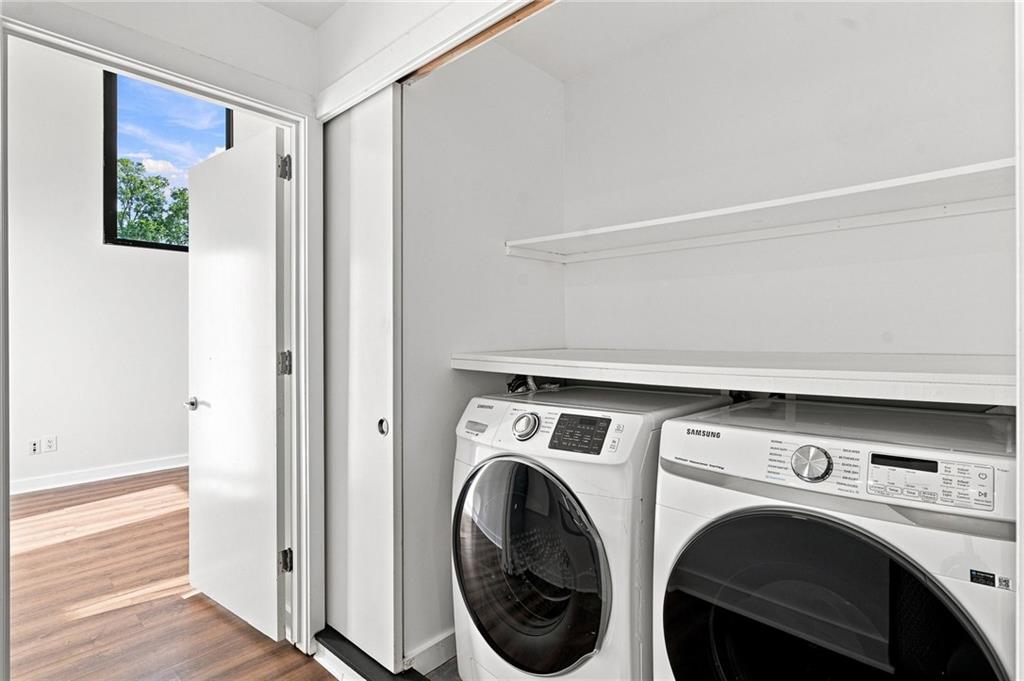 Laundry area with front-loading washer and dryer beneath a shelf, beside an open doorway.