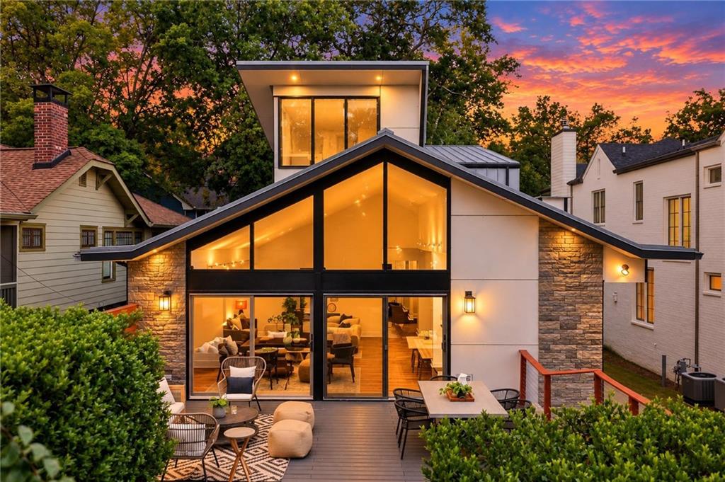 Modern home with a glass-fronted gable and furnished deck at dusk.