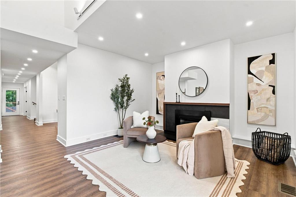 Staged living room with a black fireplace, round mirror, and neutral seating.
