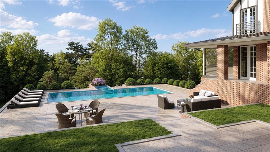Outdoor pool terrace beside a brick house, with lounge chairs, patio seating, and mature trees.