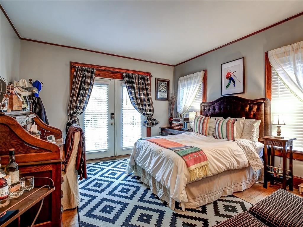 Furnished bedroom with French doors, plaid curtains, and a blue-and-white geometric rug.