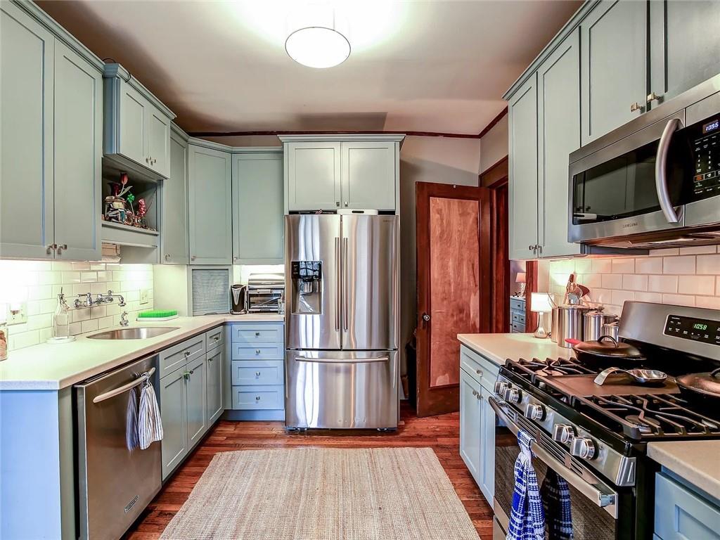 Kitchen with pale blue cabinets, stainless steel appliances, and a large gas range.