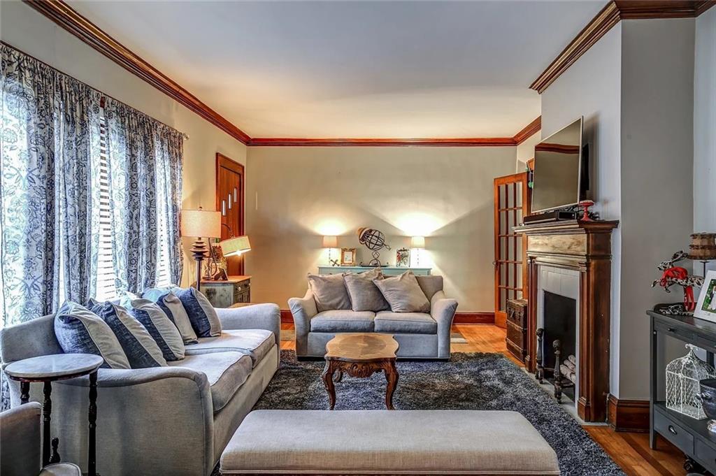Living room with gray sofas, patterned curtains, and a wood-trimmed fireplace beneath a television.