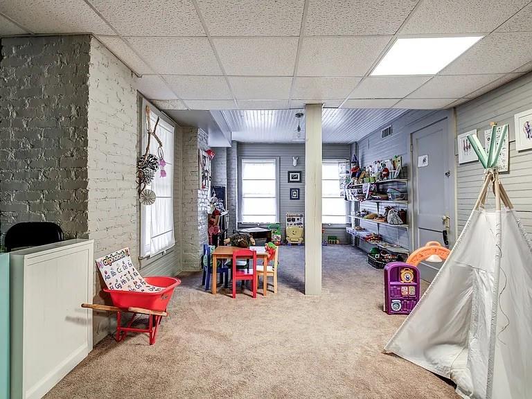 Playroom with toy shelves, a small table and chairs, exposed brick, and a white play tent.