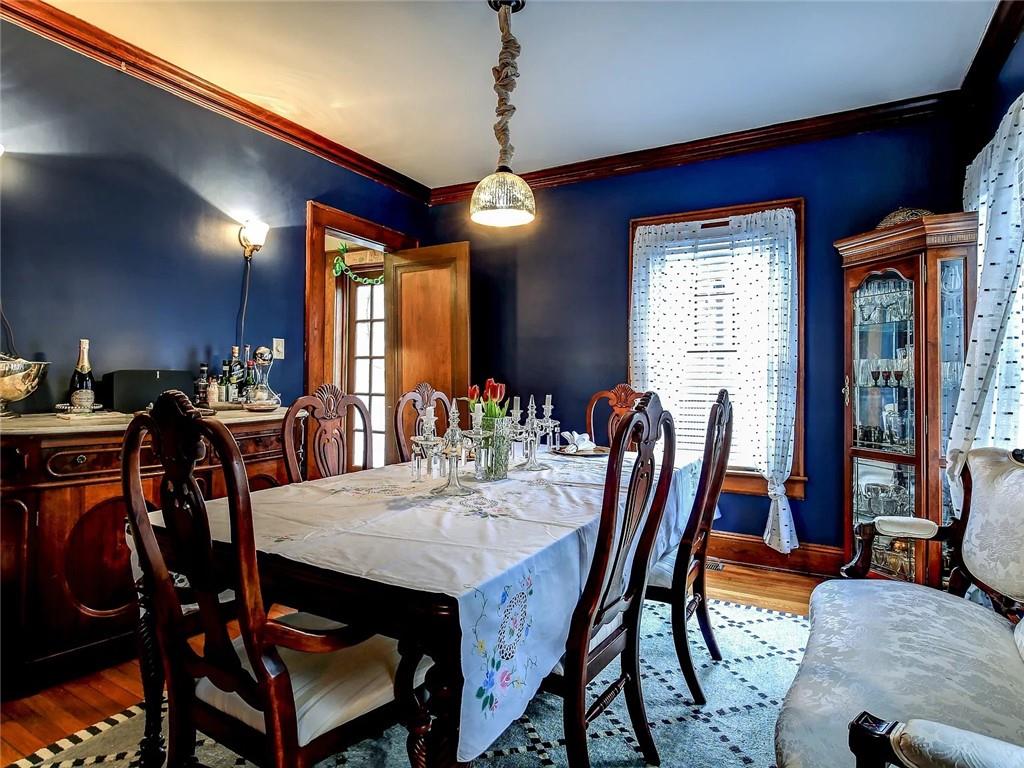 Dining room with deep blue walls, ornate wood trim, and a large table set beneath a pendant light.