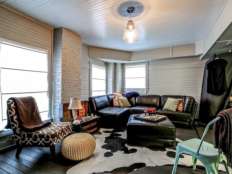 Living room with a black leather sectional, patterned chair, and tall windows.