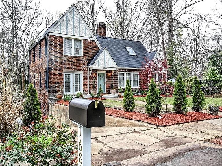 Two-story red-brick house with steep gables, front landscaping, and a mailbox beside the driveway.
