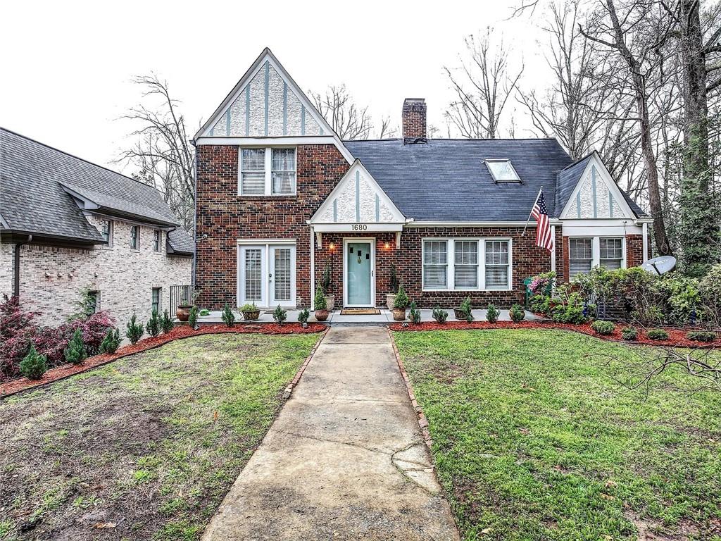 Red-brick house with white-trimmed gables, pale blue door, and a walkway through the front lawn.