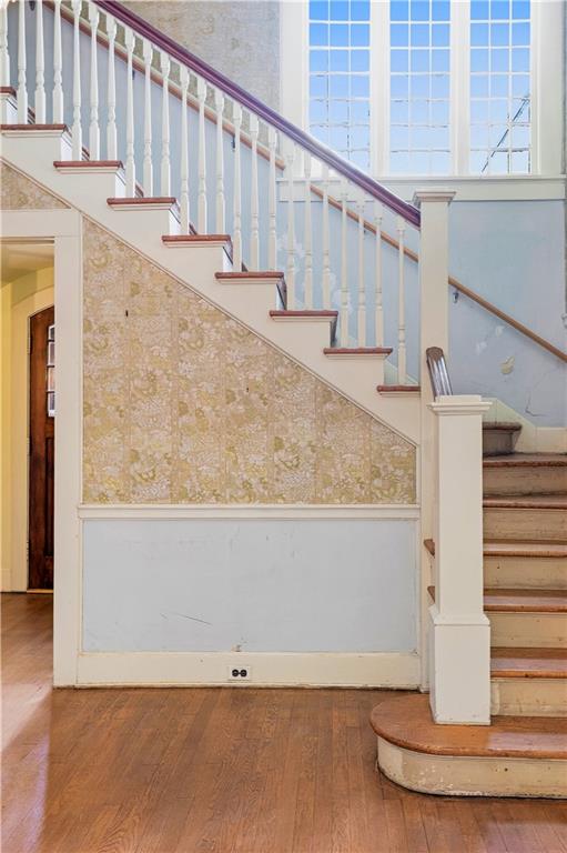 Foyer staircase with white balusters, patterned stair wall, wood steps, and tall grid-pane windows.