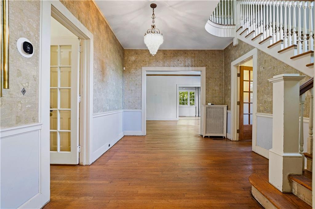 Entry hall with hardwood floors, chandelier, and curved staircase with white balusters.