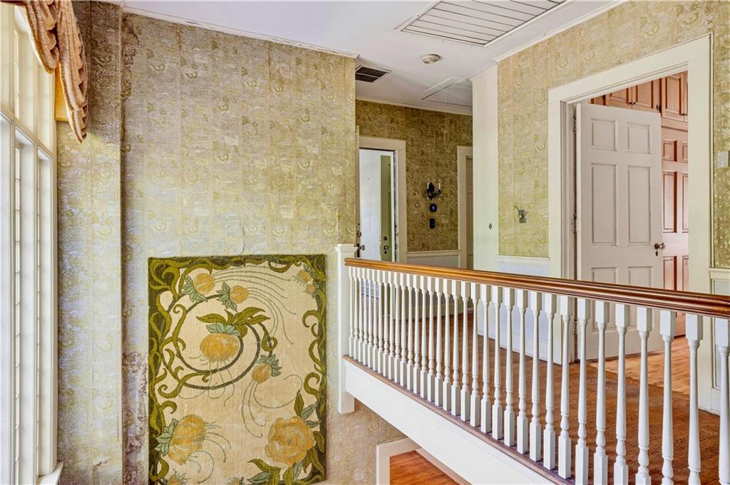 Upper landing with a white balustrade, patterned walls, and an open paneled doorway.