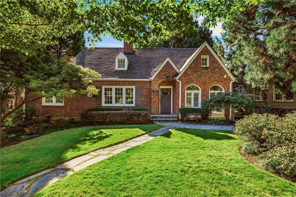Red-brick house with arched windows, a stone walkway, and a leafy front yard.