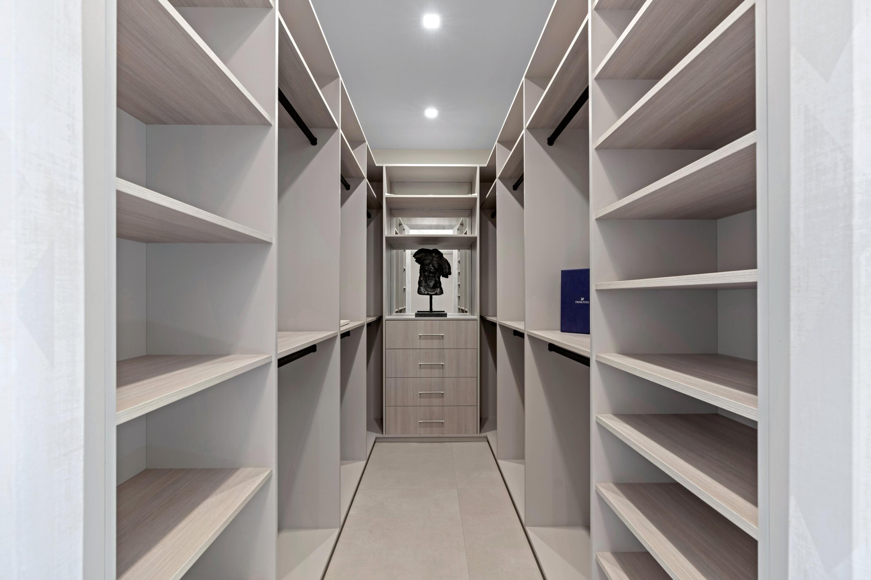 Walk-in closet with symmetrical built-in shelving and a central drawer unit.