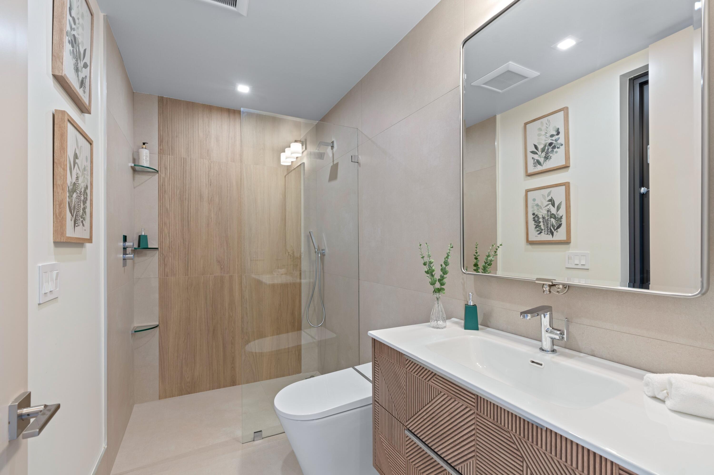 Bathroom with a glass shower, freestanding tub, and wood-front vanity beneath a large mirror.