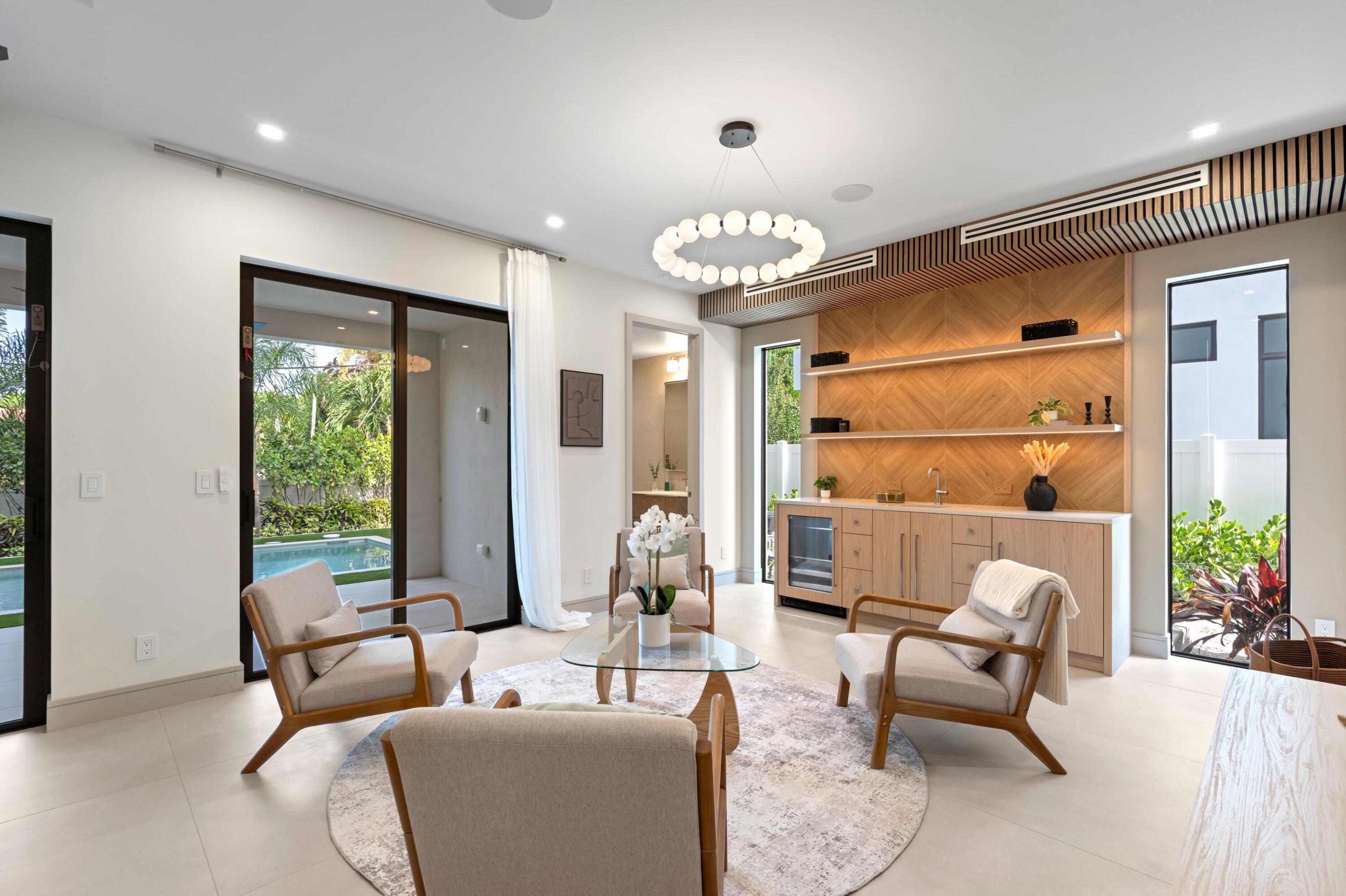Staged living room with sculptural wood bar cabinetry and sliding doors overlooking a pool.
