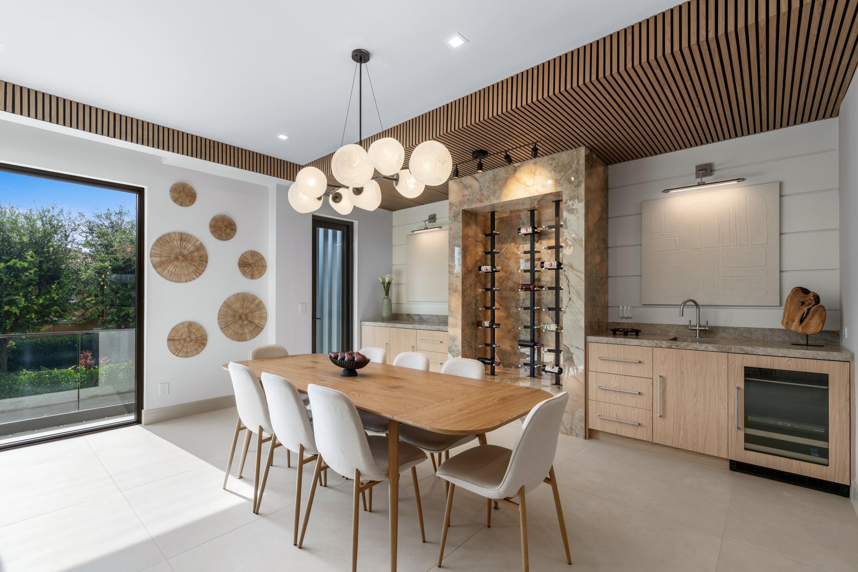 Dining room with a sculptural wine display, wood table, and sliding glass doors to greenery.