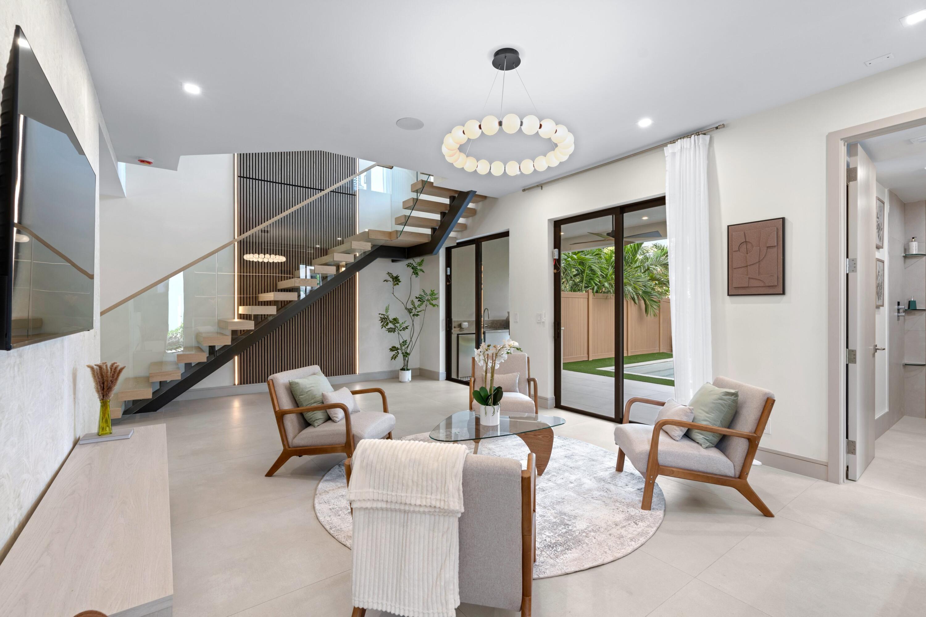 Staged living room with sculptural staircase, glass doors, and contemporary seating.