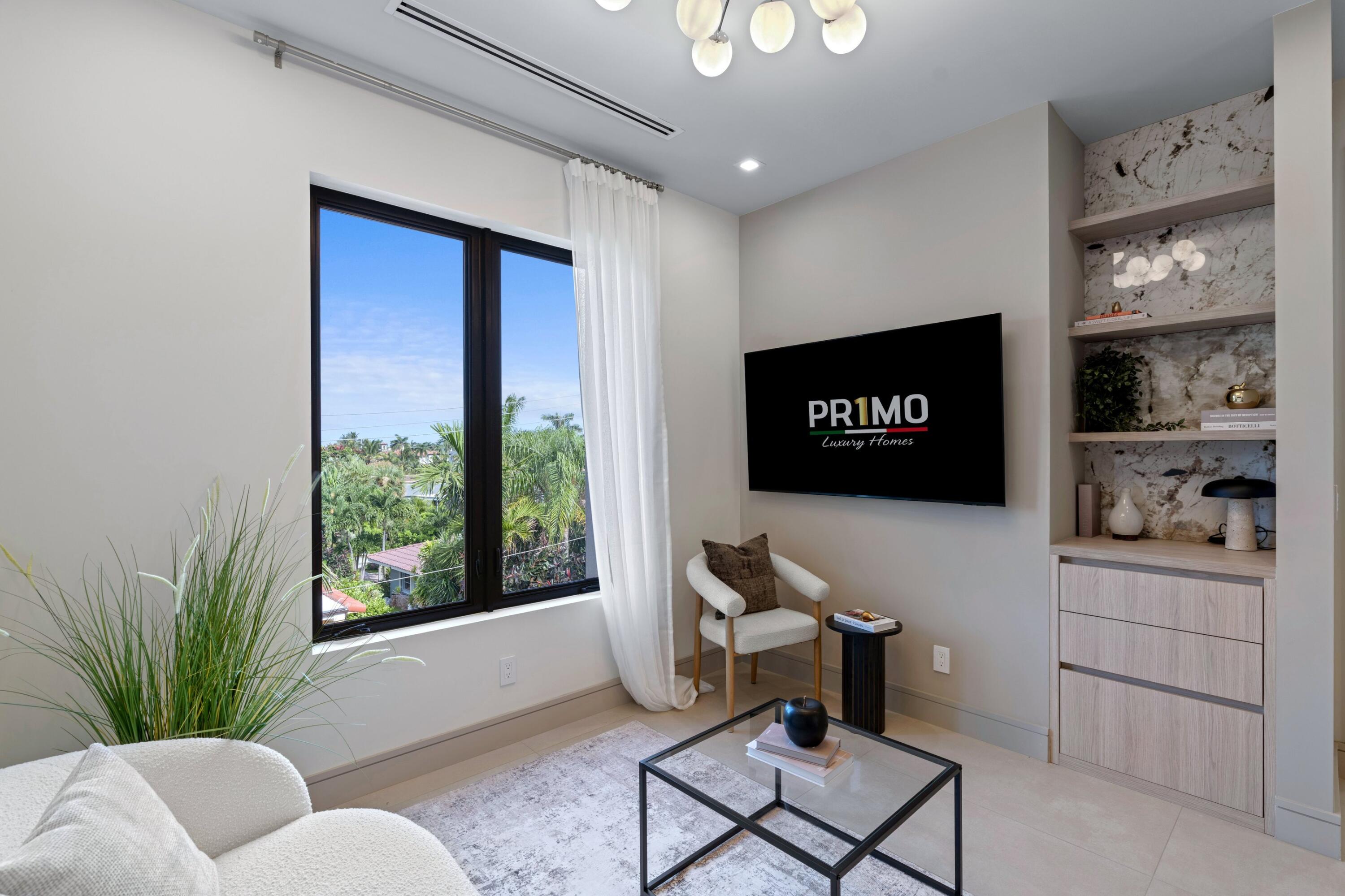 Furnished sitting room with a large window overlooking palm trees and a built-in media wall.