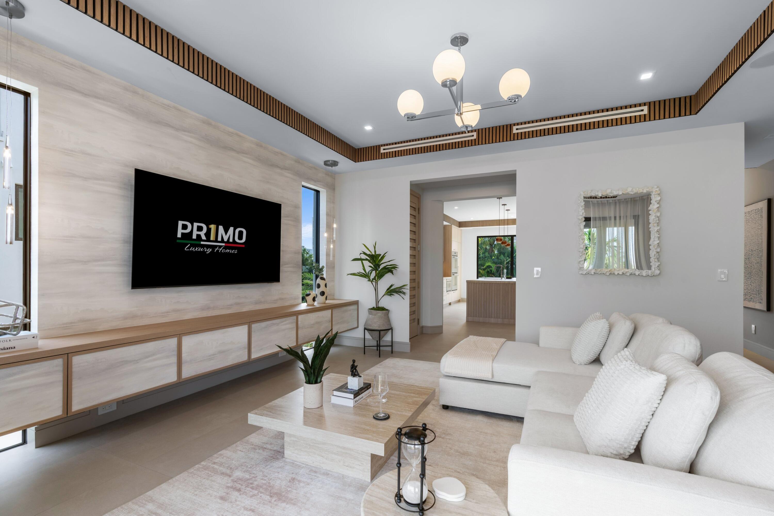 Living room with a white sectional sofa, built-in media wall, and view through to the kitchen.