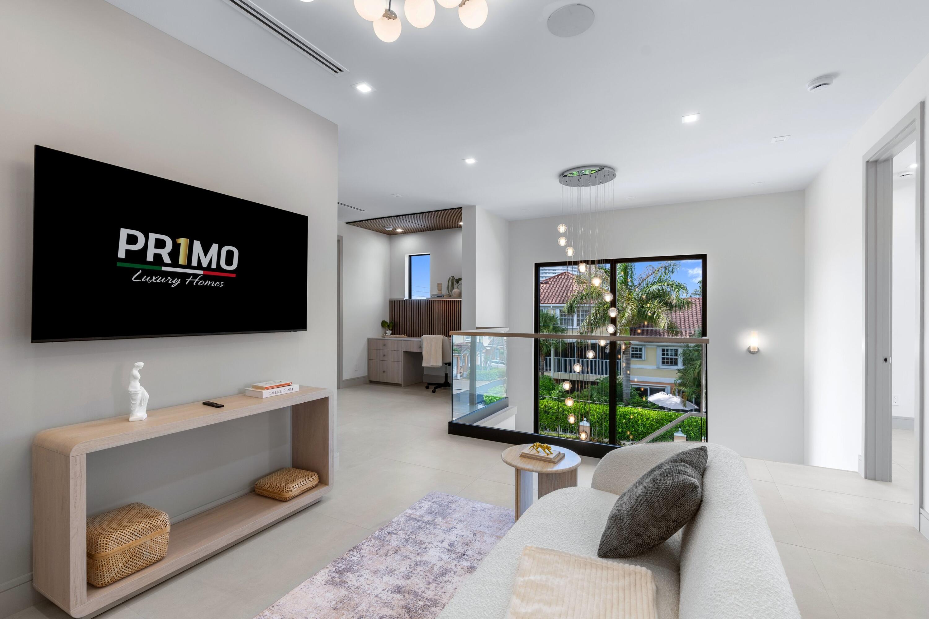 Bright living room with a curved sofa, glass railing, and floor-to-ceiling windows overlooking palm trees.