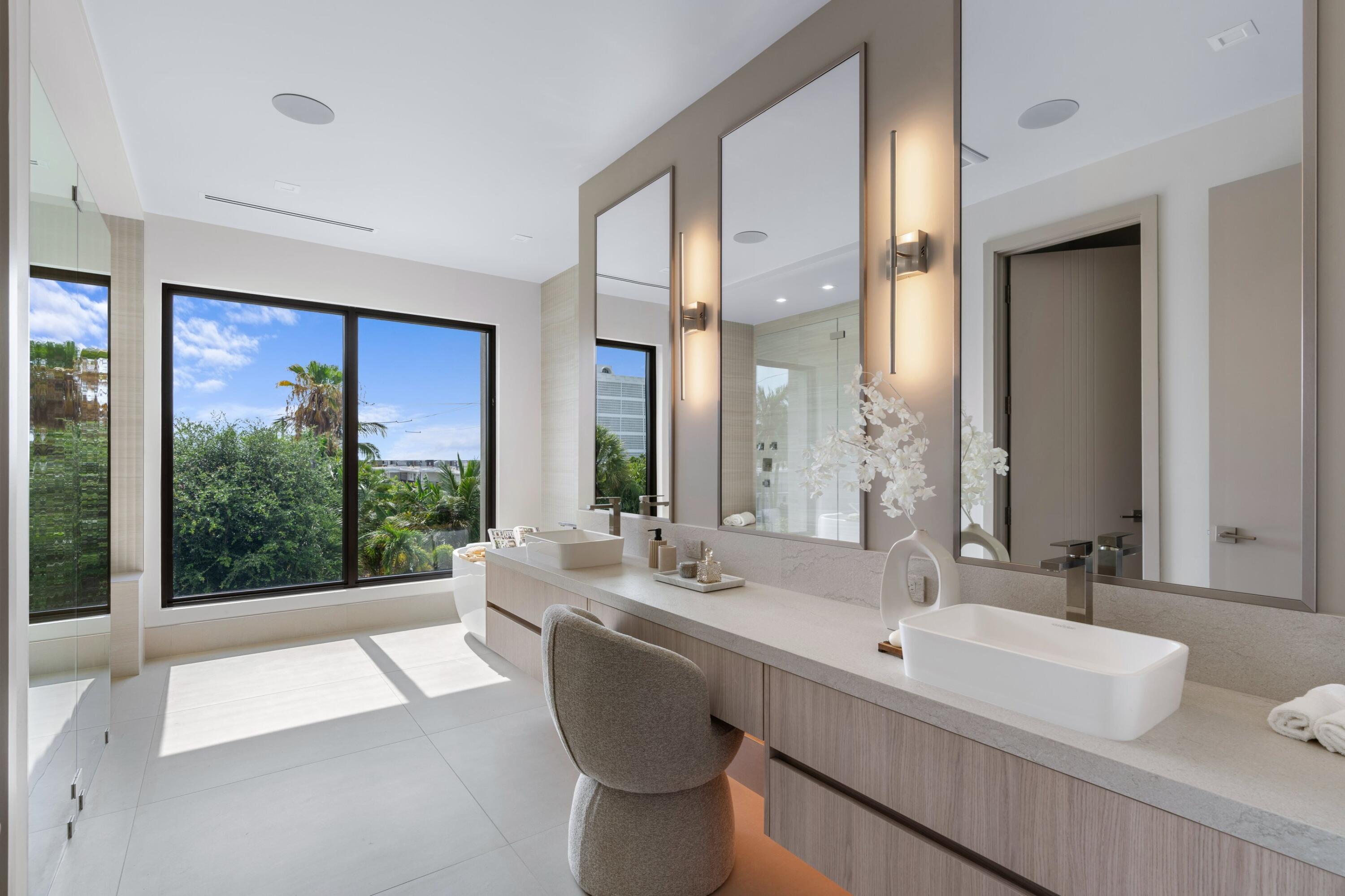 Modern bathroom with a long double vanity, vessel sinks, and large windows overlooking tropical greenery.