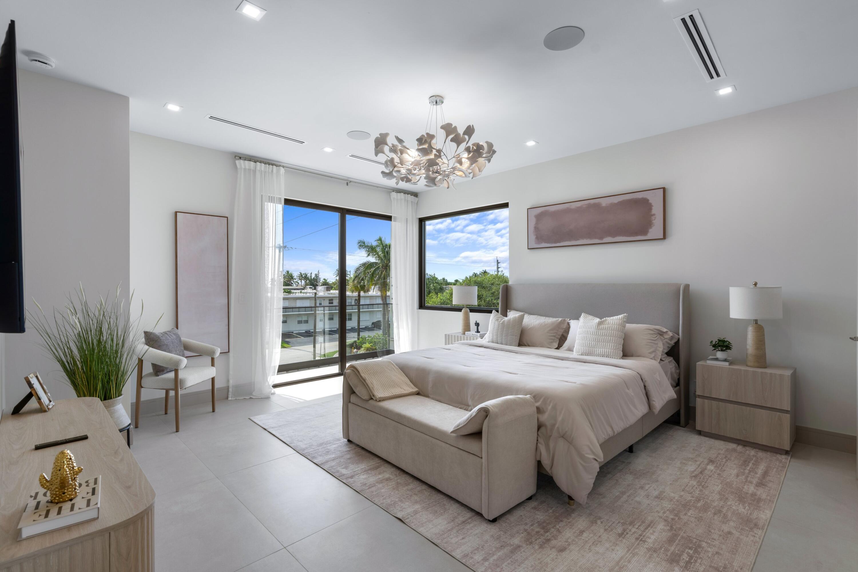 Staged bedroom with a king bed, corner windows, and a balcony view.
