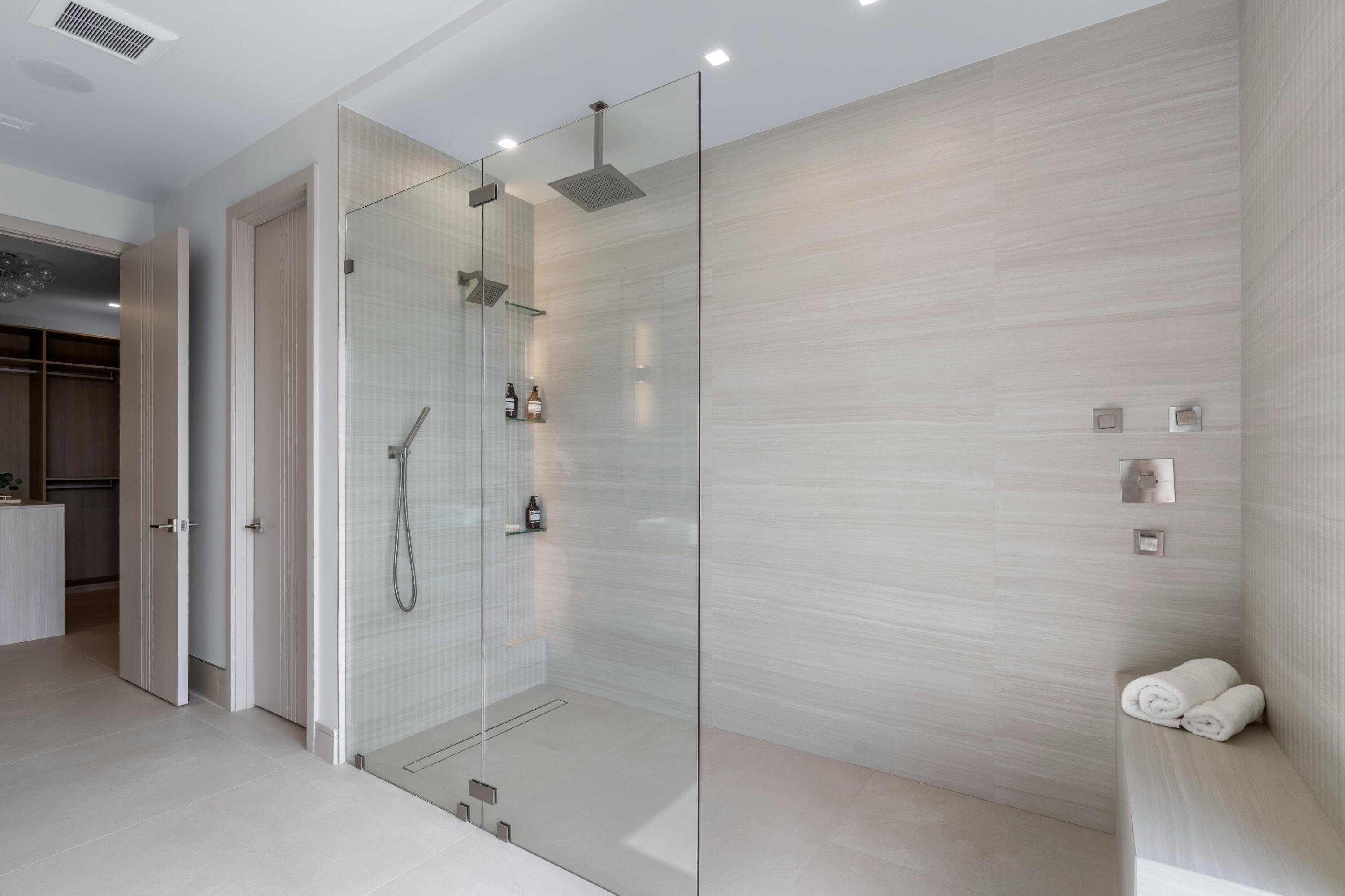 Walk-in shower with clear glass enclosure, dual showerheads, and built-in bench.