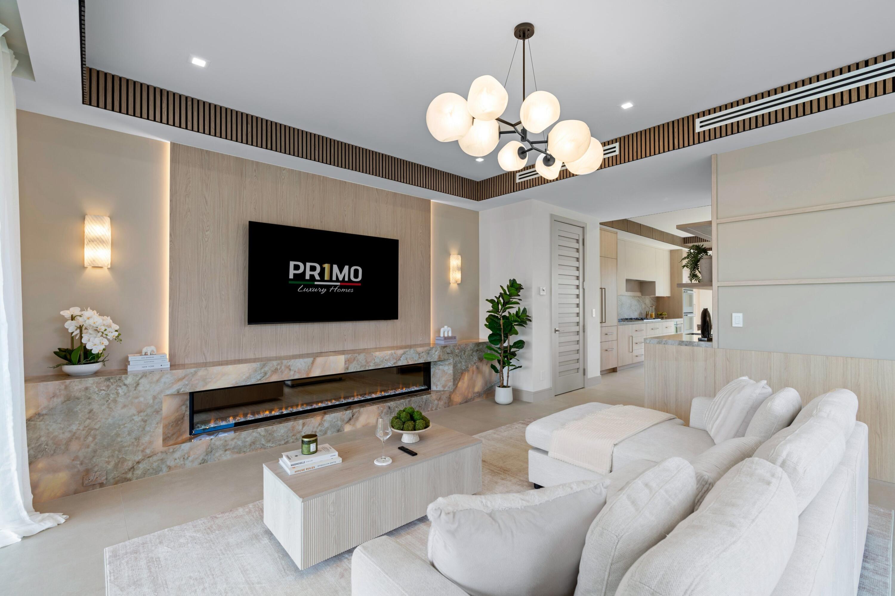 Staged living room with sculptural chandelier, marble fireplace wall, and white sectional sofa.