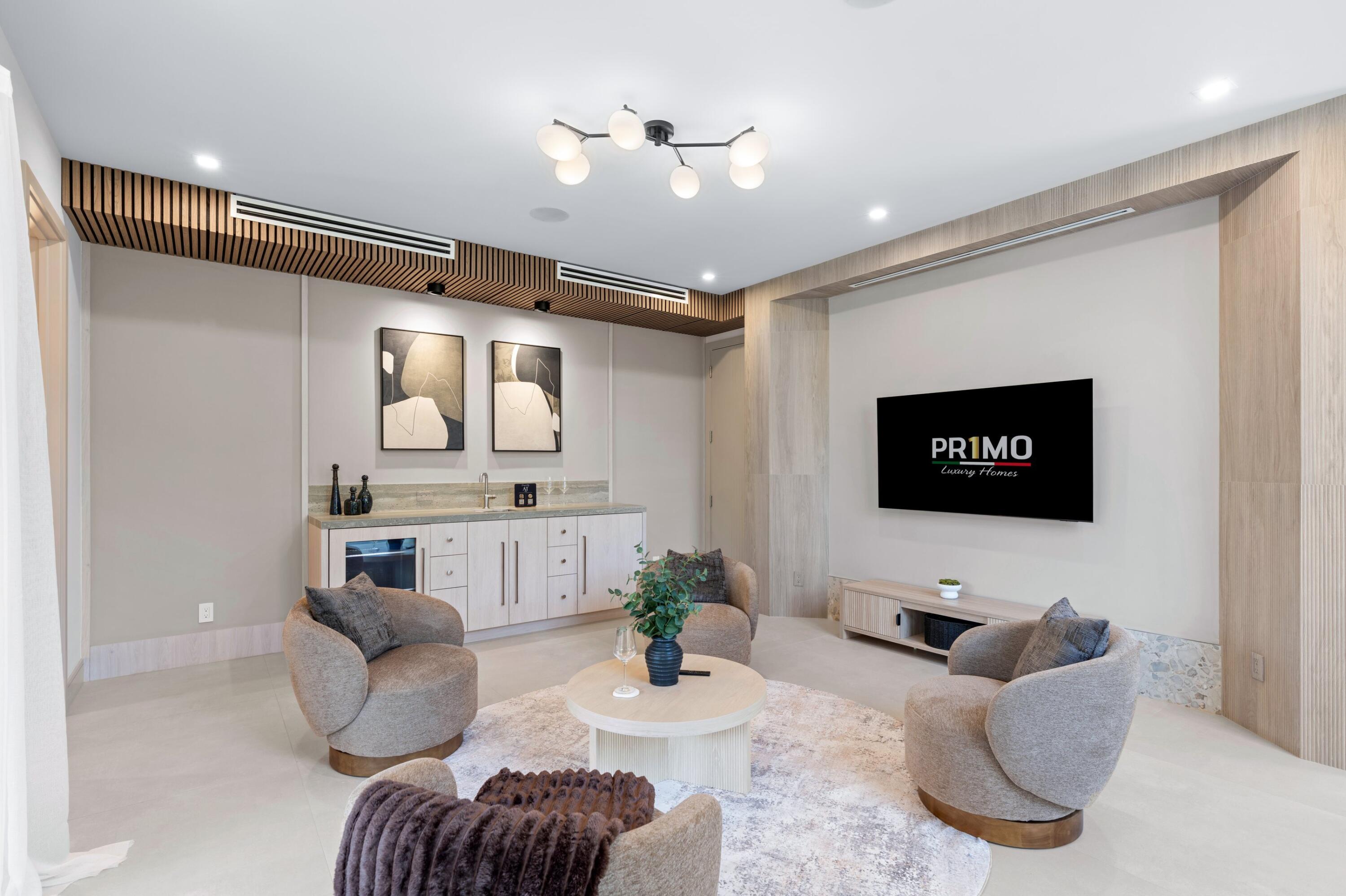 Furnished lounge with sculptural chairs, a built-in bar, and a wall-mounted television.