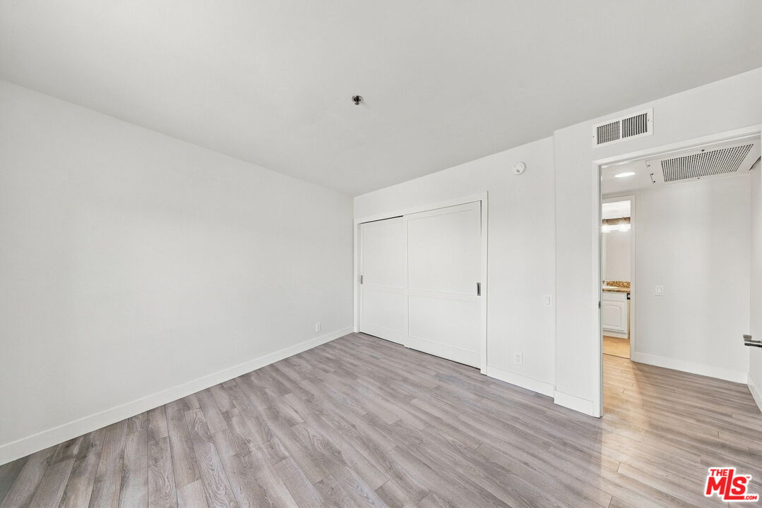 Vacant bedroom with gray wood-look flooring and a white sliding-door closet.