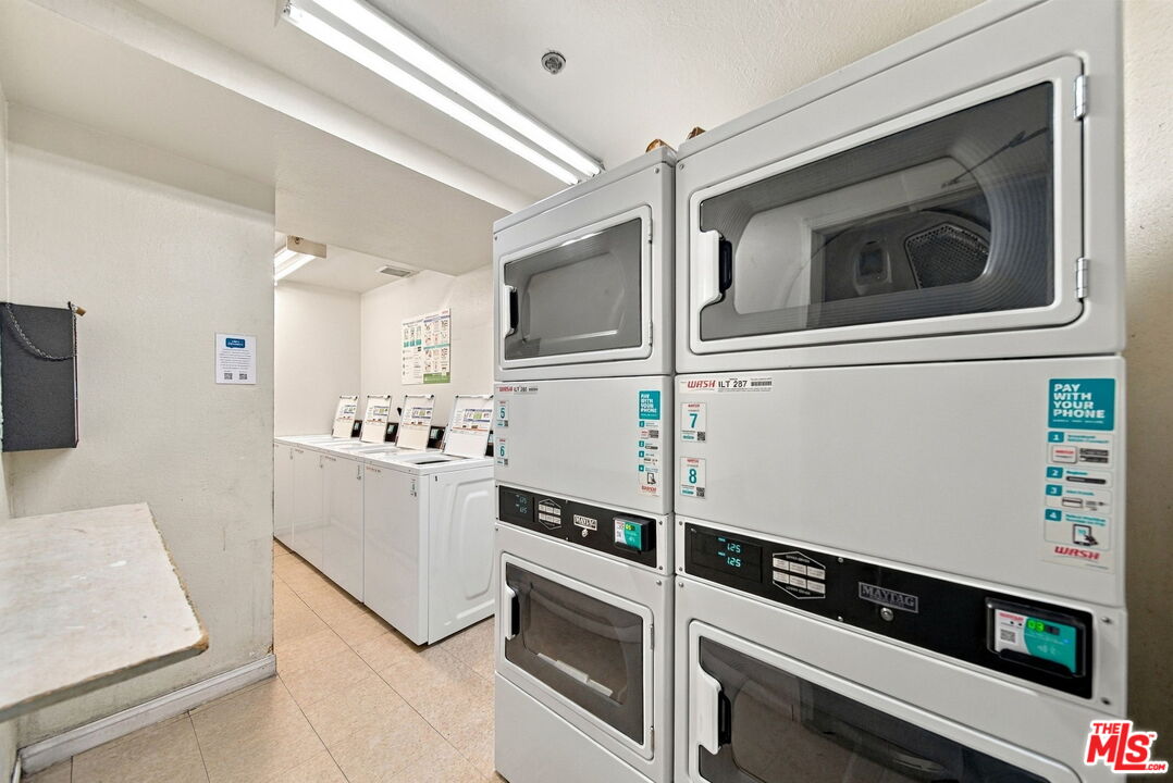 Shared laundry room with commercial washers and stacked dryers.