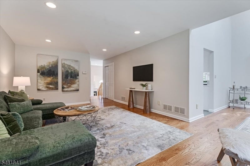 Staged living room with a green sectional, patterned rug, and hardwood floors.