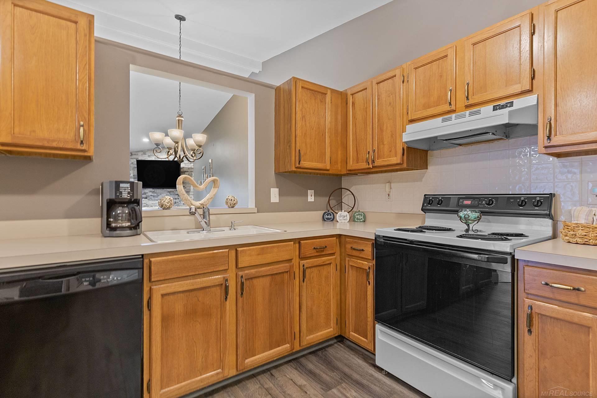 Kitchen with honey-colored cabinets, an electric range, and a wide opening to the living area.