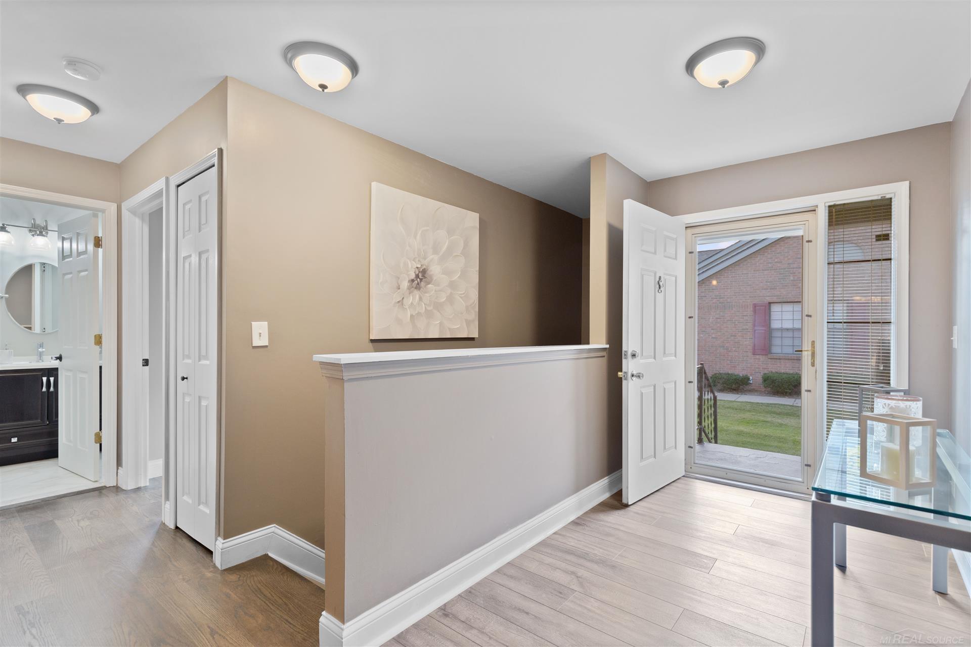 Home entryway with a white half wall, glass-panel front door, and bathroom doorway.