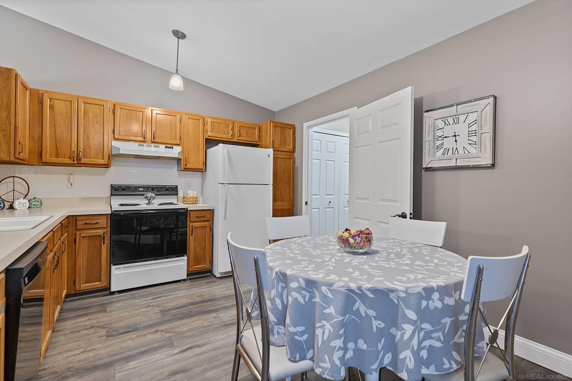 Kitchen and dining area with wood cabinets, white appliances, and a round table with a blue floral cloth.
