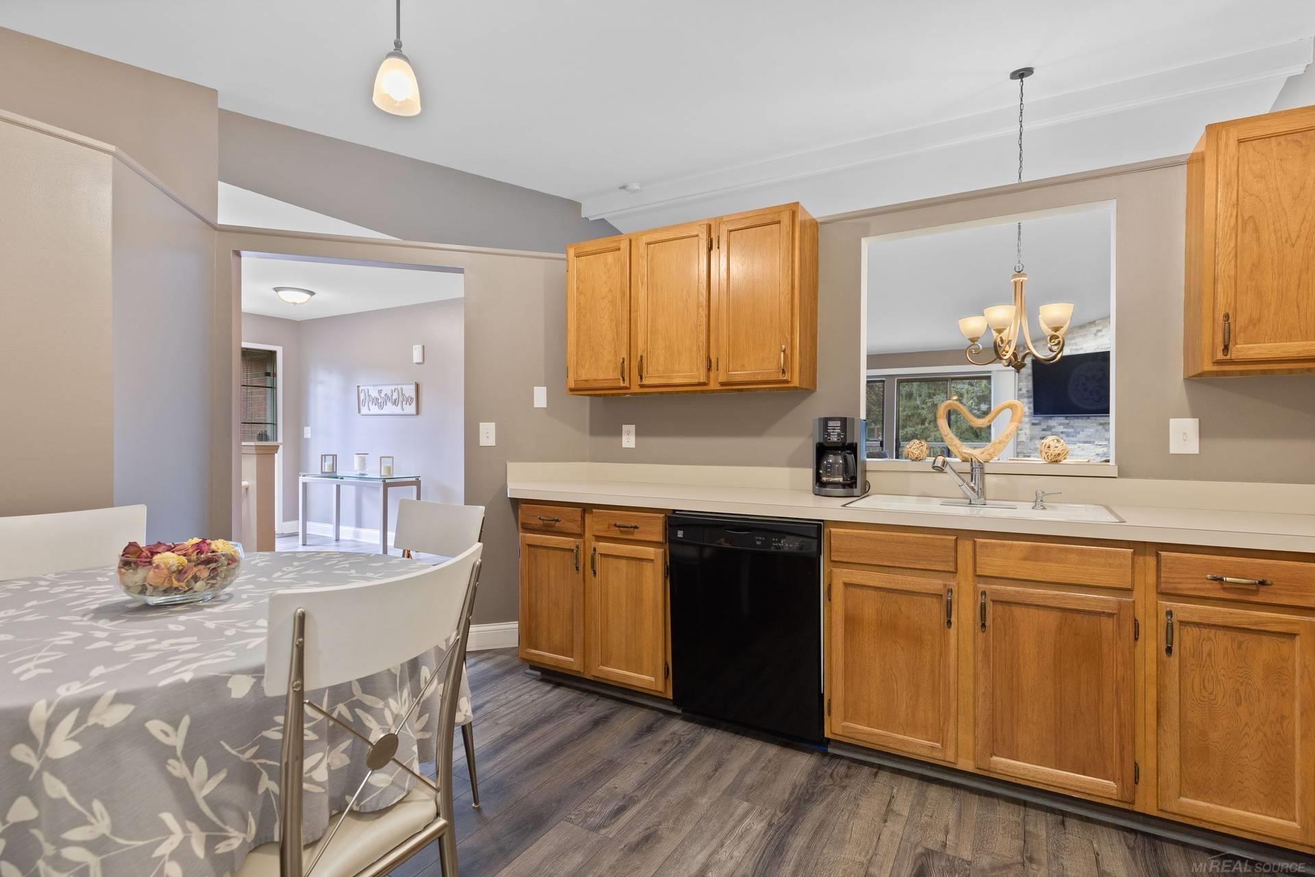 Kitchen with honey-colored cabinets, a black dishwasher, and an adjoining dining area.