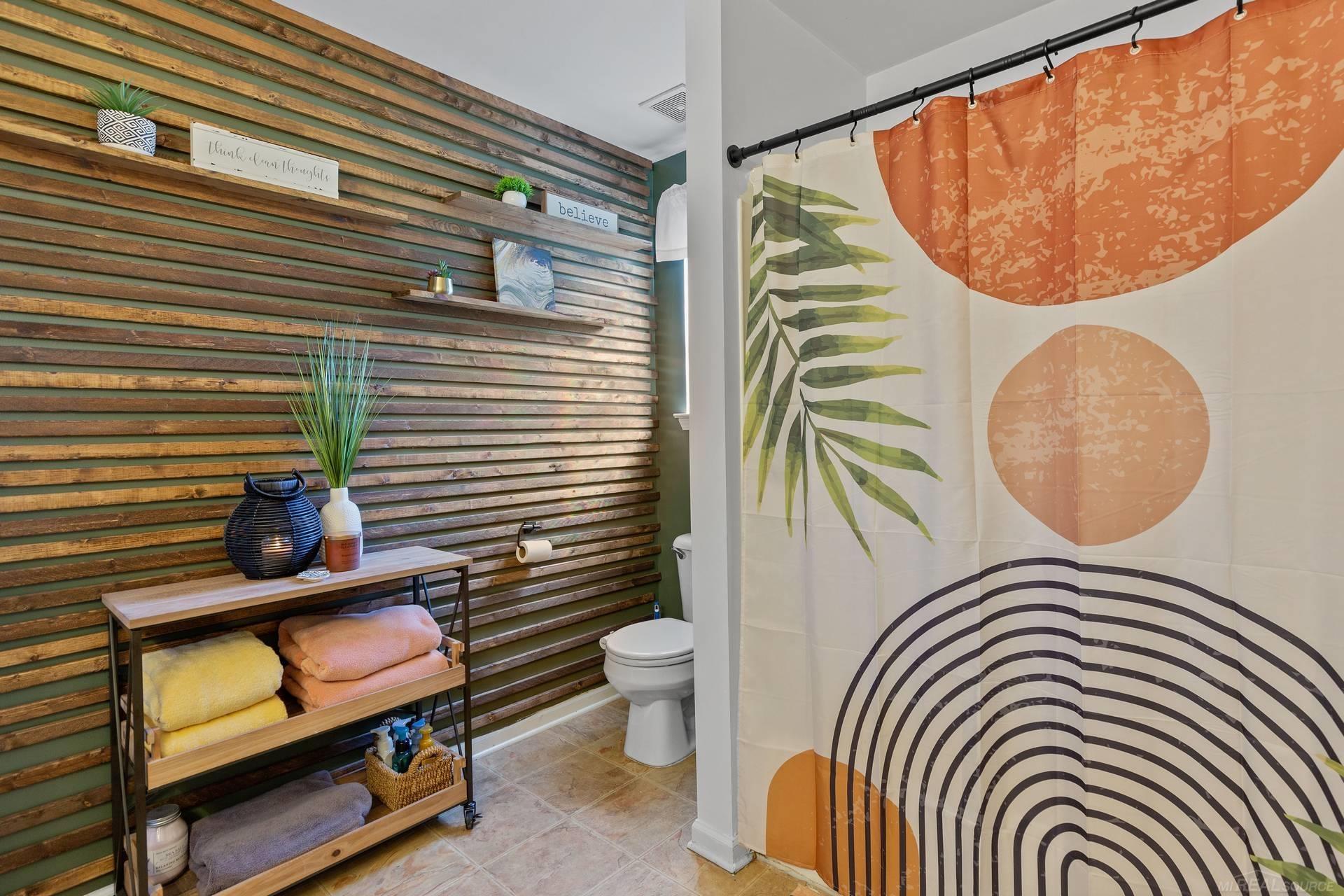 Bathroom with a geometric shower curtain and reclaimed-wood accent wall.