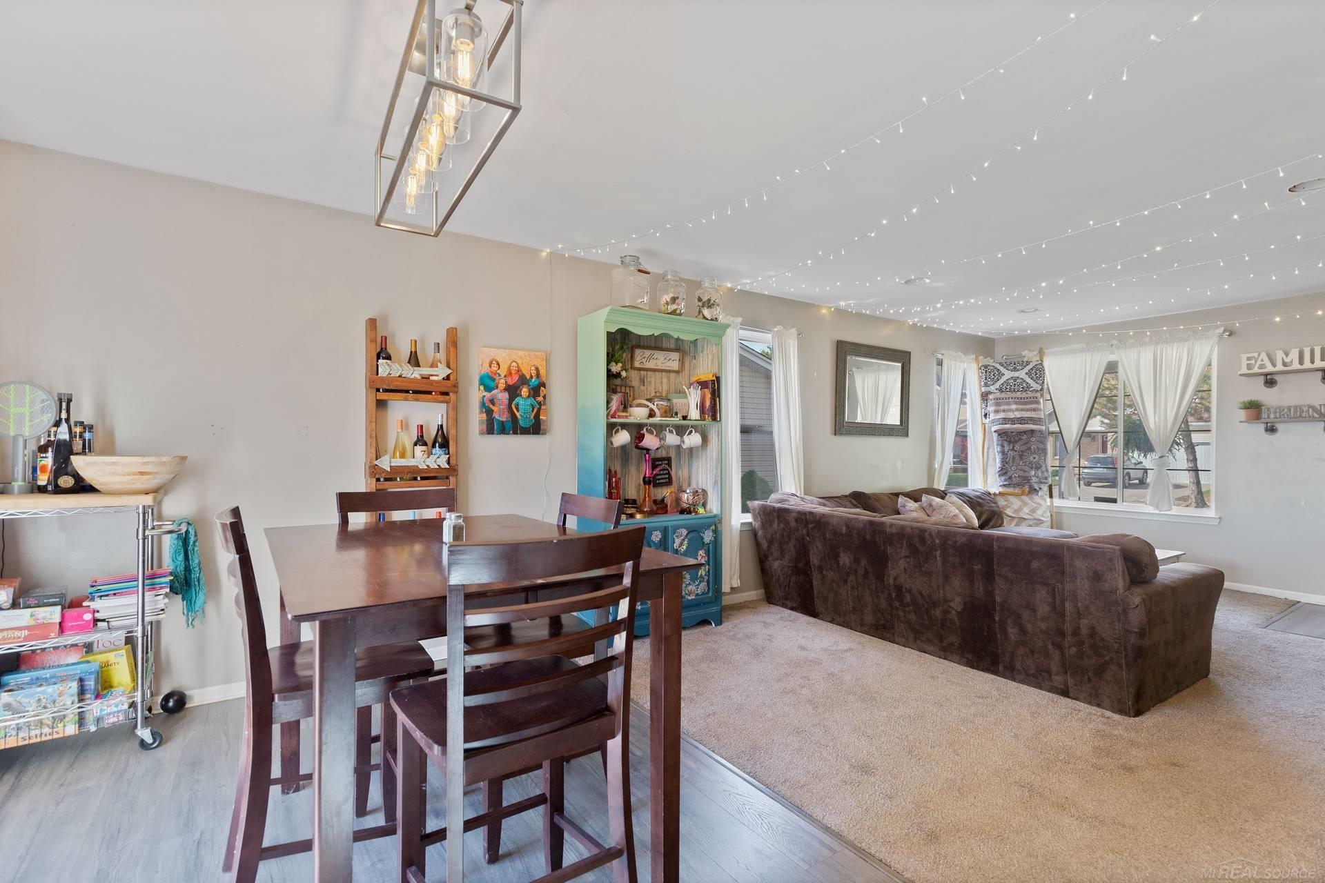 Living and dining room with a turquoise coffee bar cabinet and ceiling string lights.