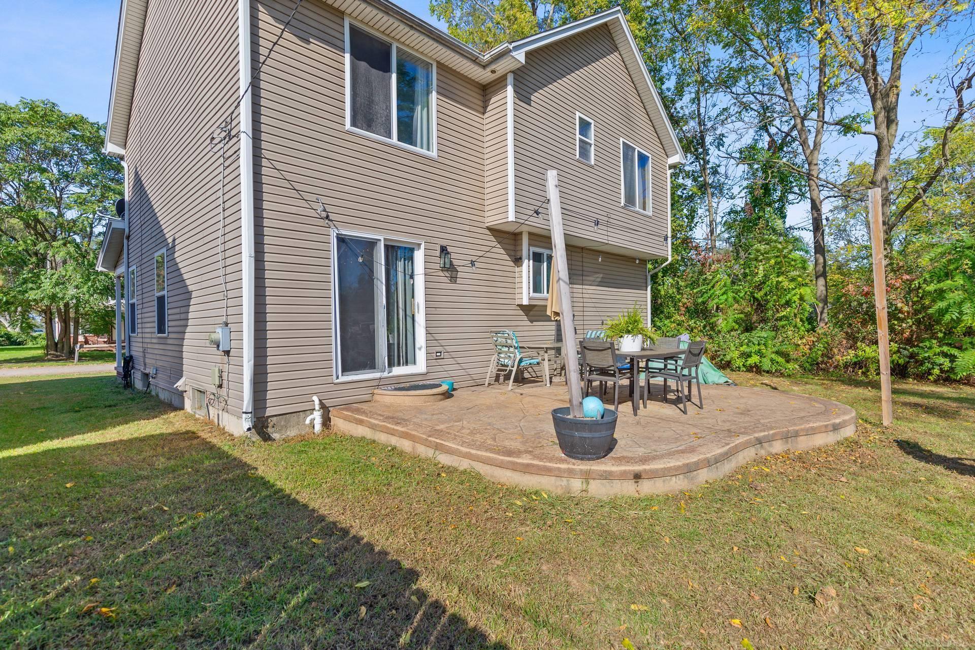 Rear of tan two-story house with a raised patio and outdoor dining set.